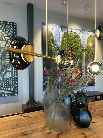 The Ceto chandelier's horizontal arm extends gracefully over a wooden table, showcasing its elegant, branching structure.