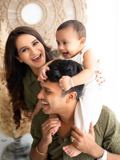 A candid family photo full of laughter and fun, with the baby getting a shoulder ride from dad.