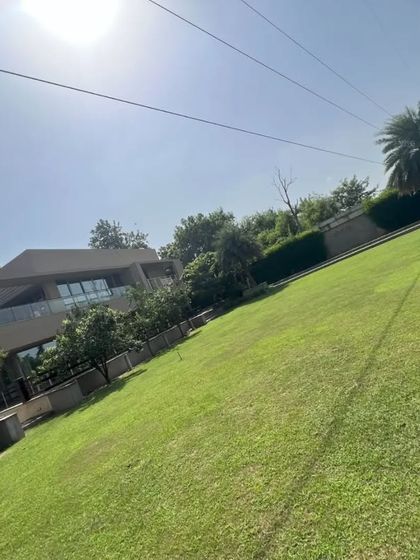 A view of a large residential property with a vast, sloping lawn. We have the expertise and equipment to install and maintain turf on challenging terrains.