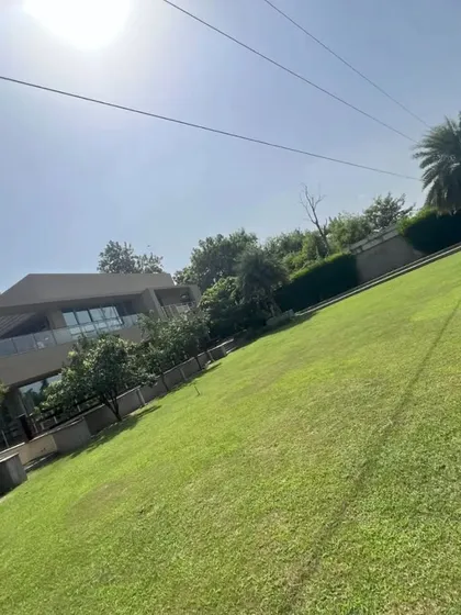 A view of a large residential property with a vast, sloping lawn. We have the expertise and equipment to install and maintain turf on challenging terrains.
