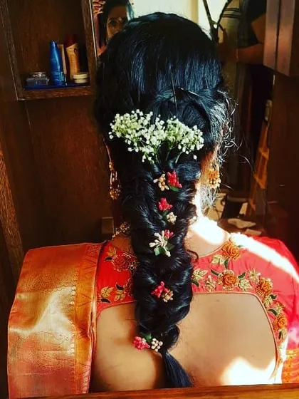 This is a beautiful fishtail braid, a popular choice for sangeet or mehendi functions. It's decorated with a mix of baby's breath and small colorful flowers for a fresh, bohemian vibe.