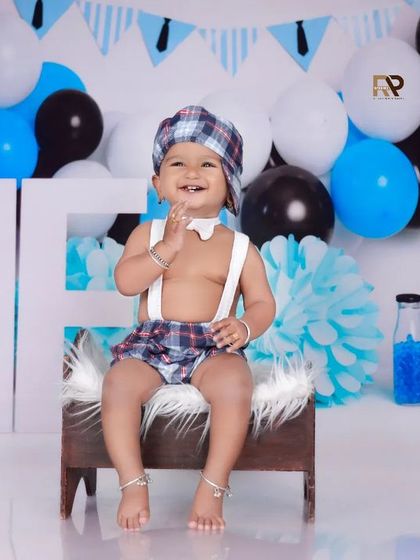 A smiling Boss Baby sits on a furry stool, looking dapper and ready for business. The blue and white theme with suspenders and a bow tie is perfectly executed.