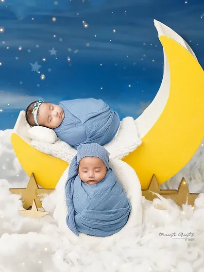 Two little dreamers on the moon. This whimsical setup features twin babies sleeping on a crescent moon, surrounded by fluffy clouds and stars.