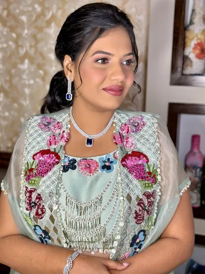 A side profile showing the soft makeup and elegant hairstyle. This is a perfect look for any wedding guest who wants to look polished and chic.