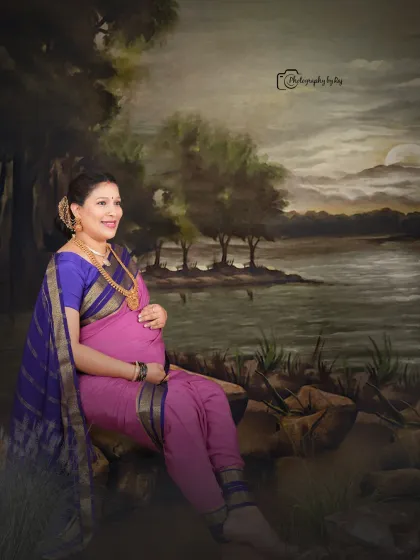 A classic Raja Ravi Varma-inspired studio portrait, with the mother-to-be seated gracefully in a traditional nauvari saree.