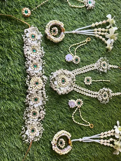 A full view of the white and green floral jewellery set. This design includes a kamarband (waist belt), necklace, hath phool, and maang tikka.
