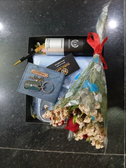 This gift hamper is packed with love, featuring a personalized denim wallet and keychain, a shirt, a pen, deodorant, and a lovely bouquet.