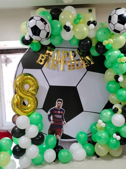 For the young football fan, this setup includes a giant football backdrop, a green, black, and white balloon arch, and cutouts of star players.