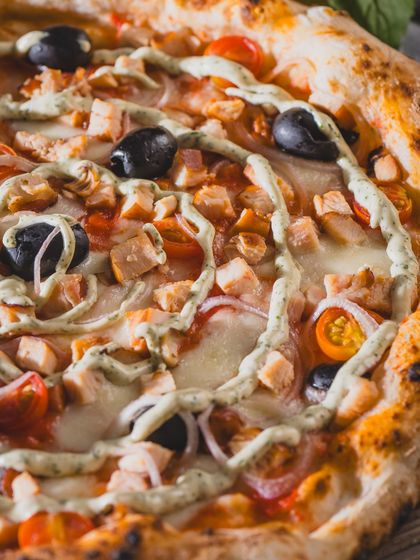 A close-up on the smoked chicken pizza, showing the creamy swirl and fresh toppings.