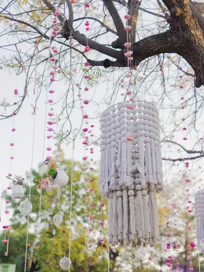 Intricate handmade macrame chandeliers and floral hangings adorn the trees, adding a bohemian and crafty touch to the whimsical decor.
