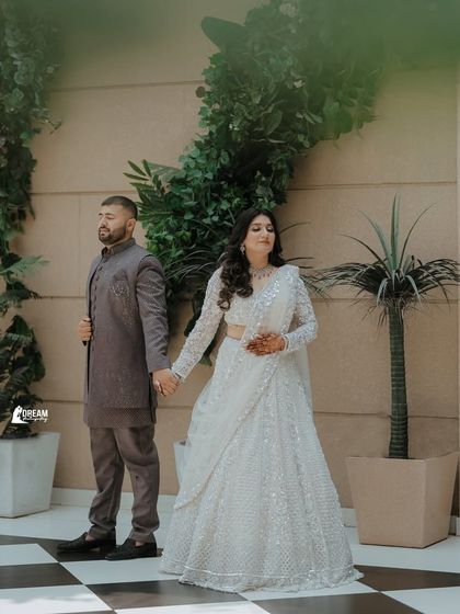 A stylish shot of the couple holding hands, showcasing their elegant outfits and the chic checkered flooring of the venue.