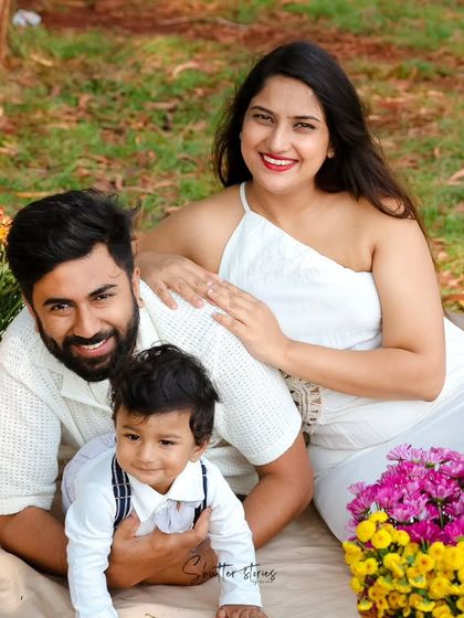 The family lies together on the picnic blanket, creating a relaxed and intimate portrait.