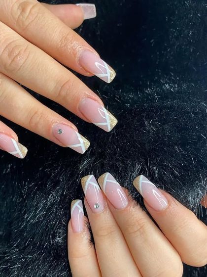 A modern geometric French manicure with white and gold glitter tips on long, square-shaped nails.