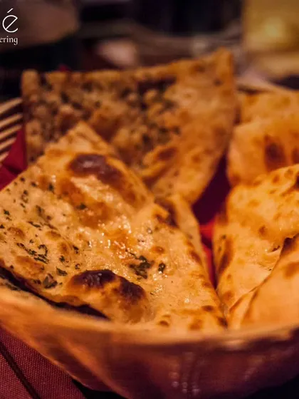 A basket of freshly made, buttered naan bread. We believe in providing the complete Indian dining experience, and fresh, soft bread is an essential part.