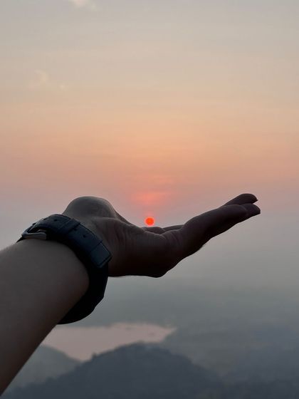 A creative shot capturing the rising sun in the palm of a hand. A magical moment on our Uttari Betta trek.