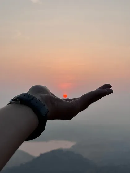 A creative shot capturing the rising sun in the palm of a hand. A magical moment on our Uttari Betta trek.