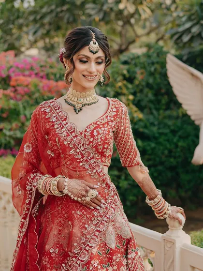 A beautiful candid shot of the bride in a garden setting. The makeup looks fresh and natural against the lush background.