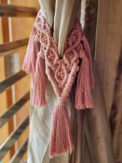 A close-up of our dusty pink macrame curtain tie holding back a curtain. It's a small detail that makes a big difference in a room's overall style.