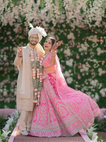 A fun and playful portrait of the couple, striking a pose and showing off their vibrant wedding attire.