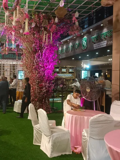 The outdoor seating area and entrance to Emerald Door banquet in Sanpada. The artificial cherry blossom tree and pink decor create a whimsical and charming atmosphere.
