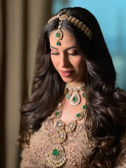 A close-up on the details. The emerald green jewellery is a stunning contrast to the gold lehenga, and her makeup is kept warm and soft to complement the look.