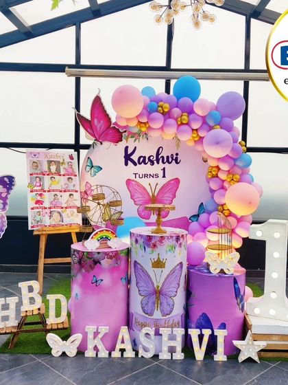 A stunning butterfly-themed first birthday on a rooftop. This outdoor setup features a beautiful balloon arch, large butterfly props, and a 'ONE' marquee table.