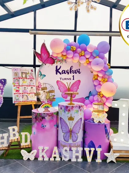 A stunning butterfly-themed first birthday on a rooftop. This outdoor setup features a beautiful balloon arch, large butterfly props, and a 'ONE' marquee table.
