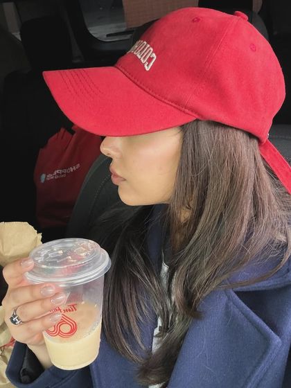 A profile shot in a car, wearing a red cap and drinking Tim Hortons coffee.
