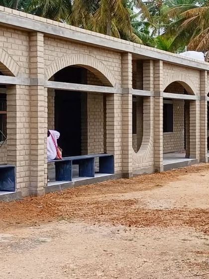 The arched corridors of Sai Kirupa Special School, built with exposed adobe blocks. These passages provide shaded seating and circulation space, connecting the classrooms to the central courtyards.