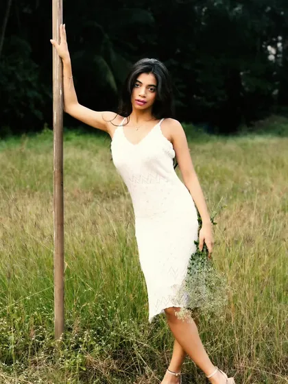 A classic, elegant pose against a wooden pole, with the lush green field stretching out behind.