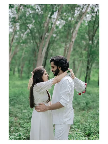 A sweet moment of the couple decorating each other with flowers in a lush forest setting.