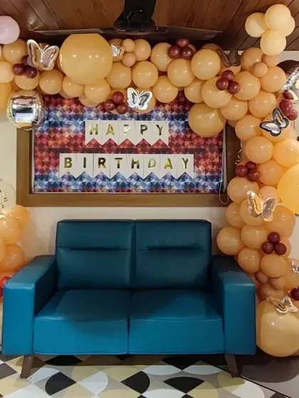A simple and elegant organic balloon garland in pastel orange and silver. This half-arch frames a seating area and is accented with butterfly cutouts, perfect for a subtle and stylish celebration.