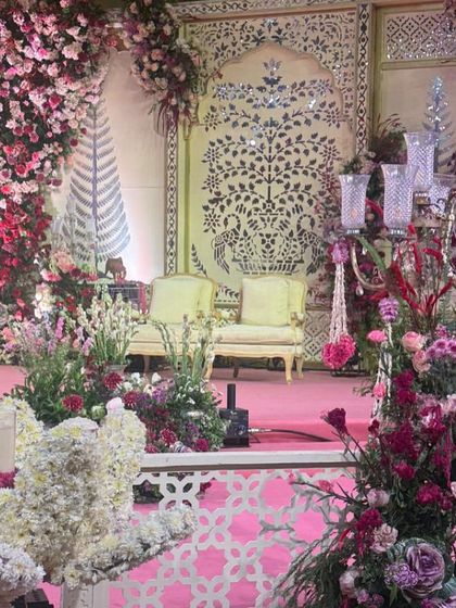 A detailed shot of the wedding stage, focusing on the lush floral arrangements and a silver candelabra. This view shows the texture and variety of flowers used, from deep pinks to soft whites, creating a rich and romantic visual.