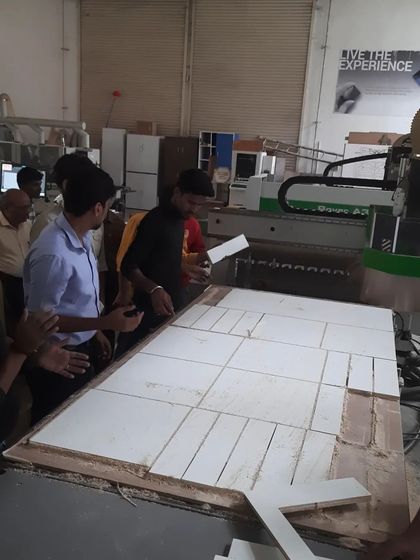 Students work together to arrange freshly cut components from a large panel processed on the CNC machine, a common workflow in modern modular furniture production.