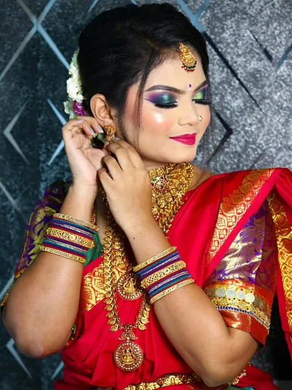A candid moment of the bride adjusting her earring, showcasing the heavy temple jewelry and the colorful bangles.