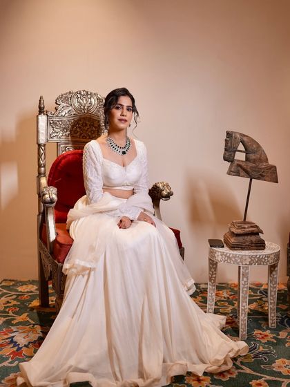 Seated on a throne-like chair, this white outfit gives off major regal vibes. Perfect for a grand wedding.