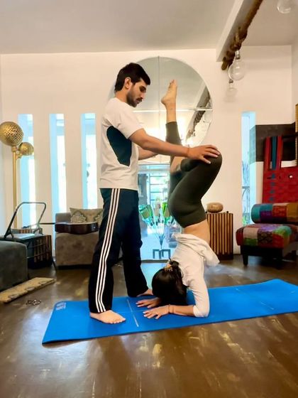 Assisting with a Lotus Forearm Balance. My role is to provide stability and alignment cues, so the student can focus on building strength and finding her balance in this challenging inversion.