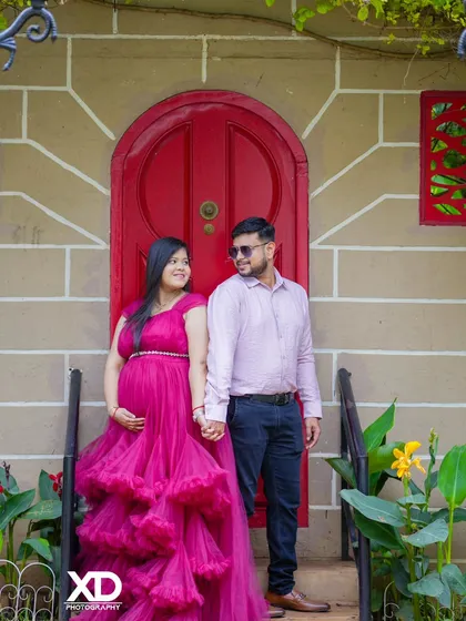 A happy couple holding hands in front of a vibrant red door, their smiles reflecting their joy.