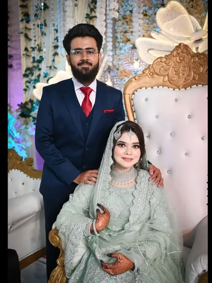 A regal portrait of the couple at their reception. The ornate chairs and their elegant attire give this photo a touch of royal sophistication.