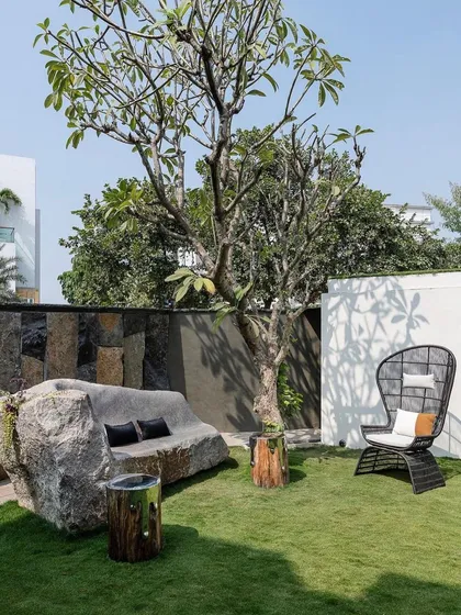I love to merge art with nature. This custom seating is crafted from a single, massive boulder, serving as both a functional bench and a powerful sculptural element within the backyard garden.