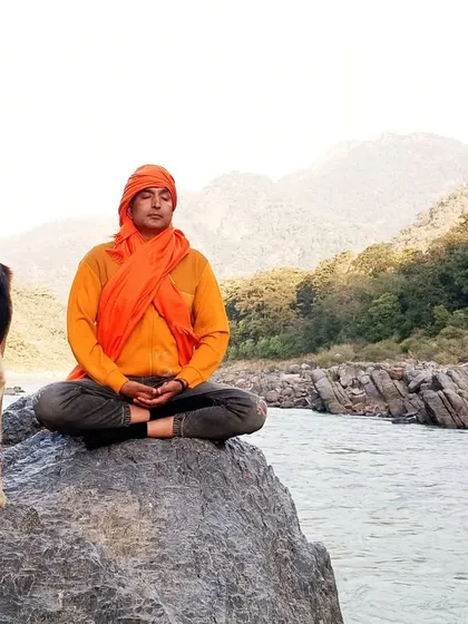 I find my peace in nature, and I guide you to find yours. Here, I am in meditation by the river in Rishikesh, a practice of connecting with the self that I share in every retreat.