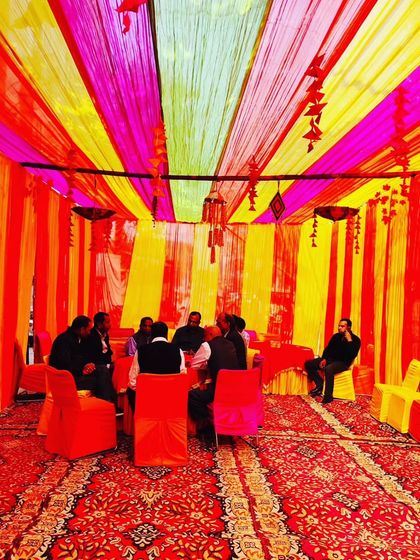 A tent interior with a red and yellow theme, showing guests seated and enjoying the celebration in a space I created.
