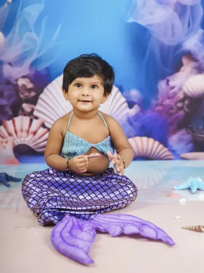 Our little mermaid, looking absolutely adorable with her purple tail and seashell backdrop. This is a very popular fantasy theme for baby girls.