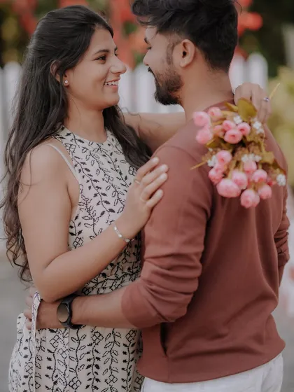 A casual stroll hand-in-hand along a path lined with a white picket fence and vibrant flowers. This image captures the simple, everyday romance that is the foundation of a great love story.