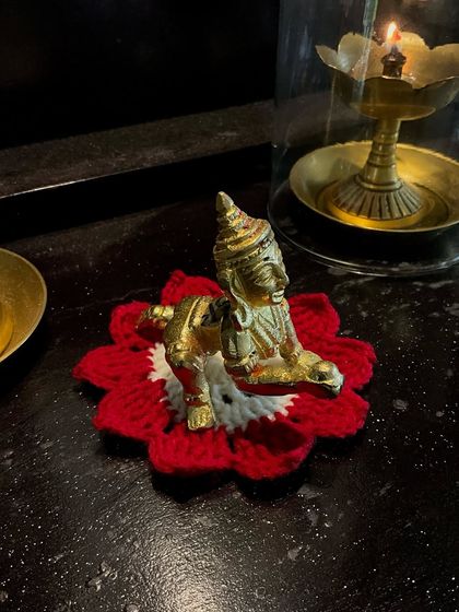 A red and white 'asan' designed to look like a lotus flower for the Krishna idol.
