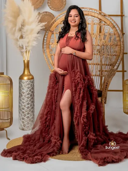 A glamorous portrait in a rust-colored gown, seated in our boho peacock chair with elegant lantern props.