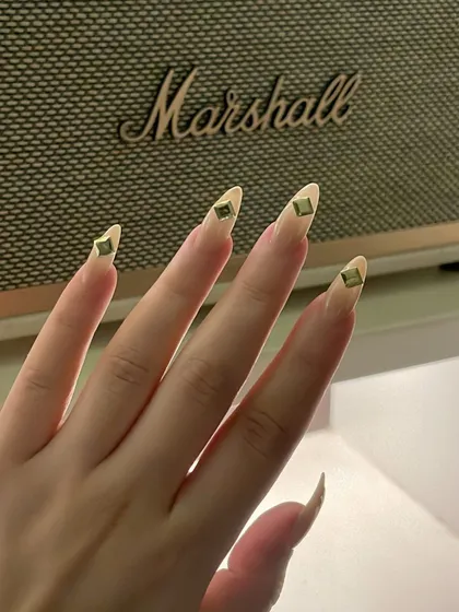 An edgy and minimalist design. These long, clear stiletto nails are accented with a single, strategically placed metal stud on each tip.