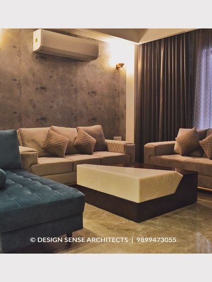 A comfortable and chic living room setup featuring a teal chaise lounge paired with neutral sofas. The textured wallpaper and warm lighting create a cozy and inviting atmosphere perfect for relaxing.