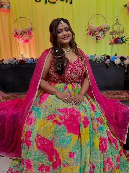 A beautiful Mehendi bride, ready for her ceremony. The makeup is bright and glowing, with a pop of pink on the lips to match her colorful outfit.
