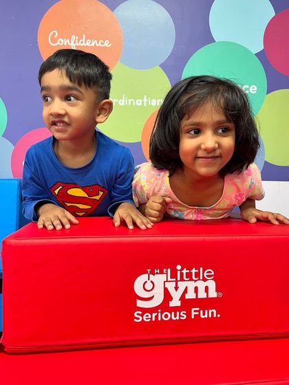 These two children, one in a Superman shirt, share a curious look. The colorful, stimulating environment of my gym encourages interaction and shared discovery.